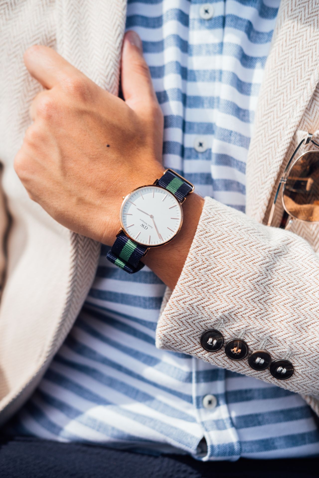 Daniel Wellington sat s prugastim platnenim remenom na ruci muškarca u bež sakou