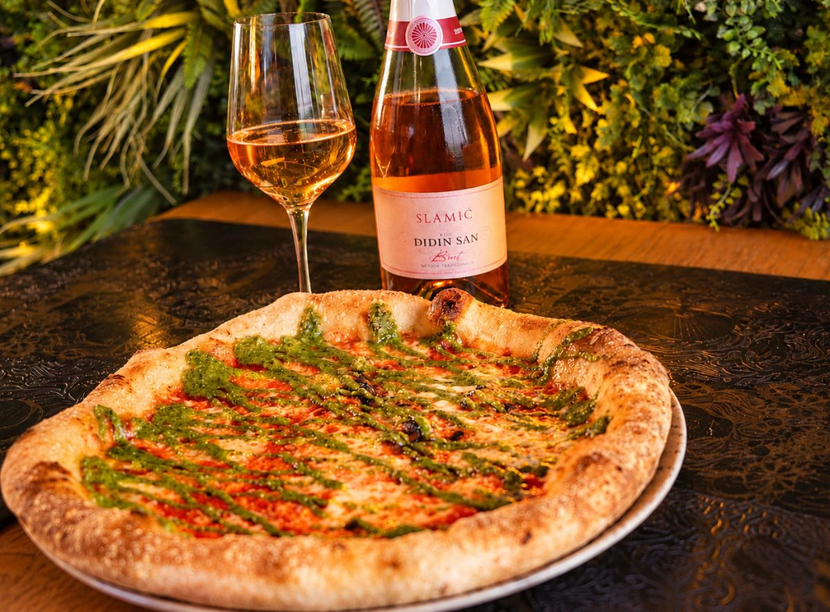 Pizza Margherita pesto Genovese poslužena uz bocu i čašu ružičastog pjenušca Slamić Didin san