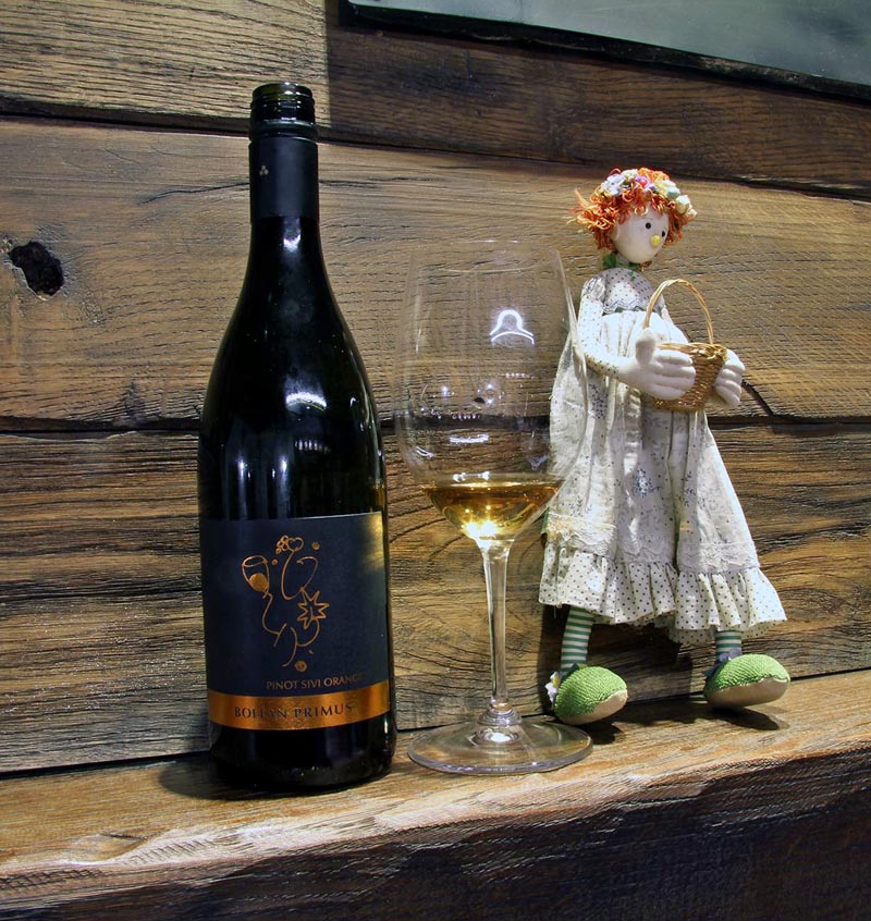 Boca Bolfan Primus Pinot Sivi Orange vina, čaša i platnena lutka na drvenoj polici
