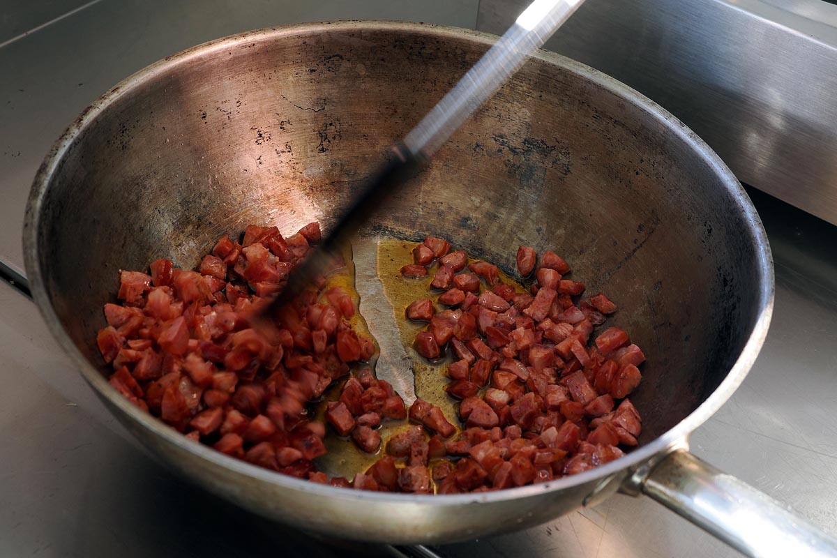 Dinstanje narezane domaće kobasice u tavi tijekom pripreme umaka za tradicionalnu puntarsku palentu