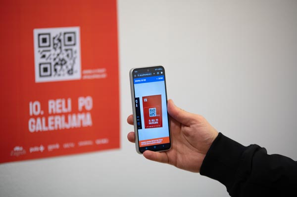 Pametni telefon skenira QR kod na crvenom plakatu za 10. Reli po galerijama