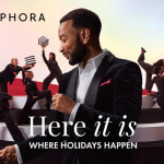 John Legend u crnom odijelu u prvom planu Sephora blagdanske kampanje s plesačima u pozadini