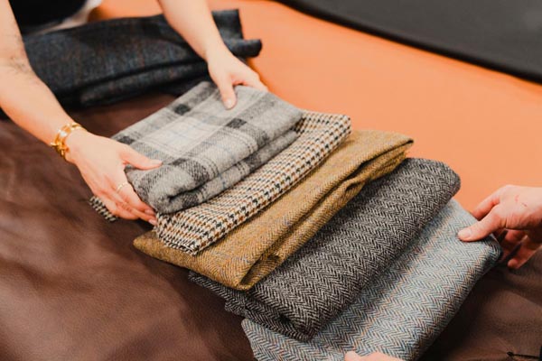 Ruke krojača slažu uzorke vunenih tkanina različitih kariranih i riblja kost uzoraka