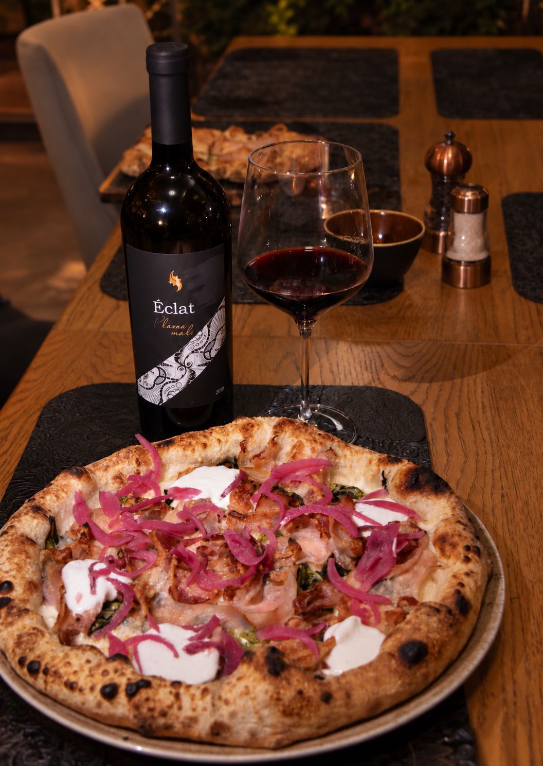 pizza Slanina Friarielli poslužena uz bocu i čašu crnog vina Éclat Plavac mali 