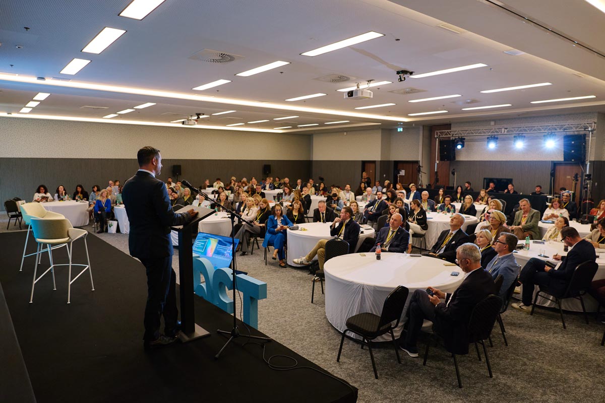Govornik za pultom na pozornici ispred brojne publike u dvorani konferencije