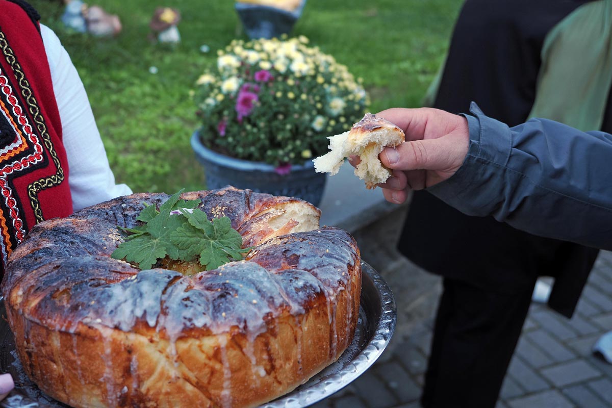 Gost trga komad tradicionalne bugarske pogače s pladnja tijekom dočeka