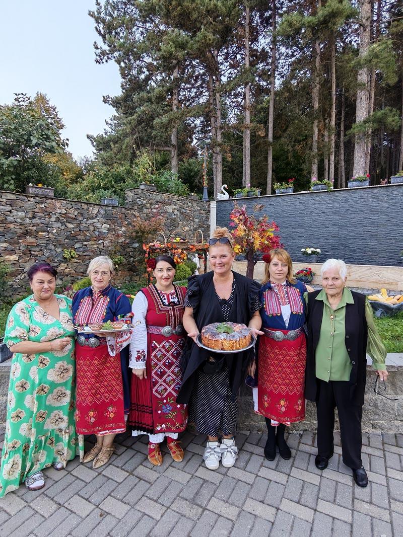 Alma Premerl Zoko i skupina žena s pogačom i u bugarskim narodnim nošnjama u dvorištu Ville Vakanica