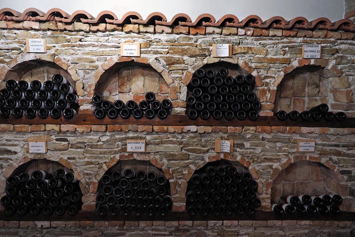 Boce arhivskog vina Melnik poslagane u kameno-ciglenim nišama starog vinskog podruma vinarije Orbelia