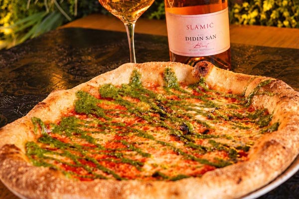 Pizza Margherita Pesto Genovese iz pizzerije Mrs. Fogg poslužena uz bocu i čašu pjenušca Slamić Didin san