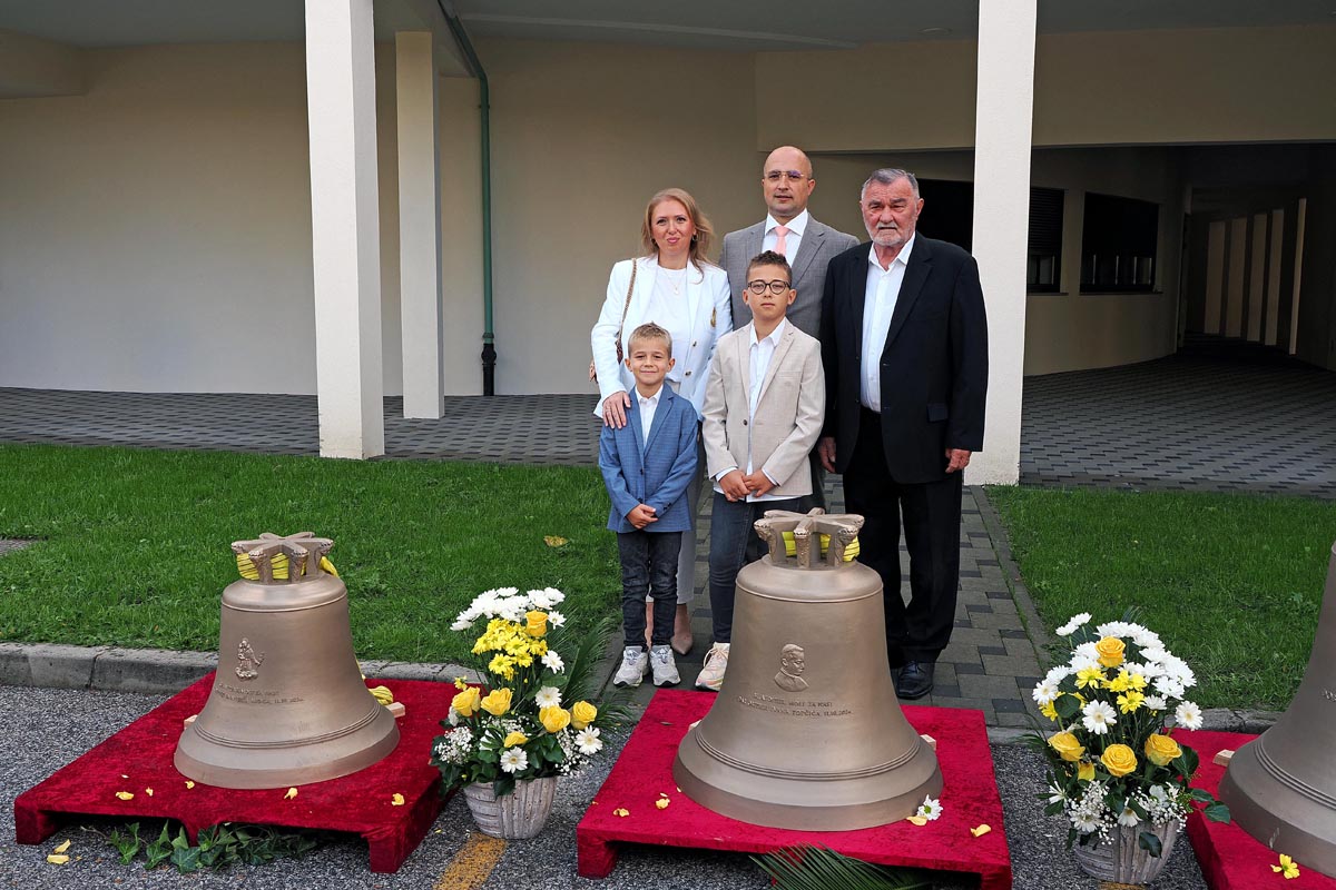 Kumovi, obitelj Mioč i Ivan Topčić poziraju uz nova crkvena zvona ukrašena cvijećem ispred župe sv. Ivana XXIII.